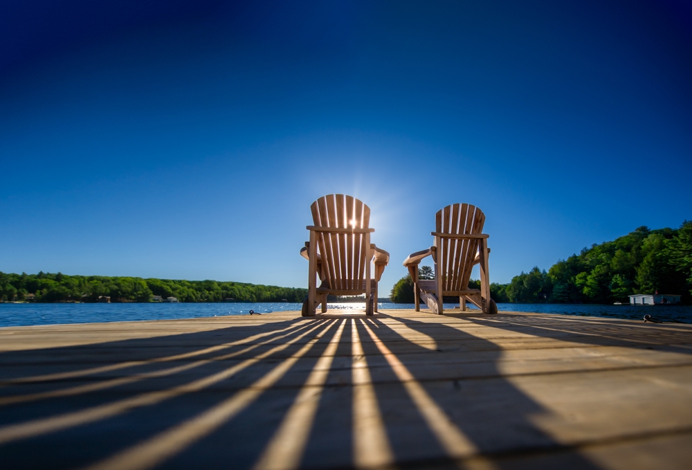 Sunrise creating shadows of two chairs on a dock in summer.