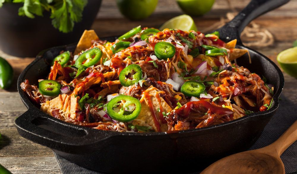 Loaded nachos in a cast iron pan.