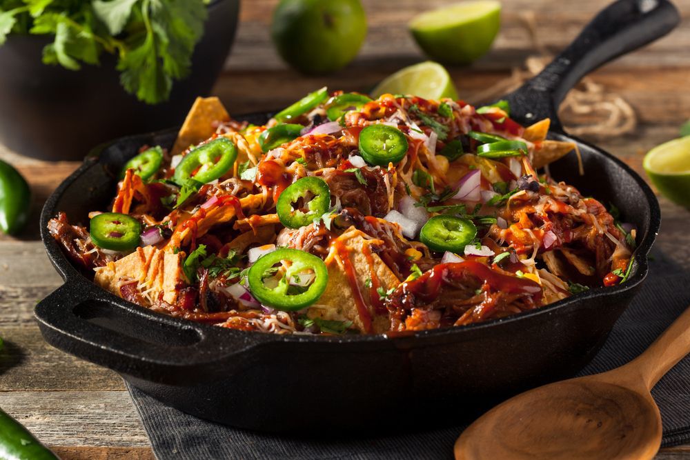 Loaded nachos in a cast iron pan.
