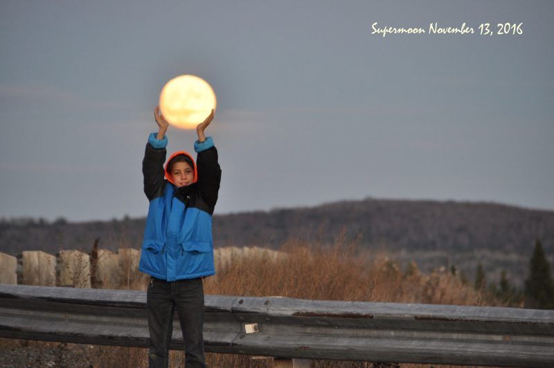 child appearing to hold up the moon