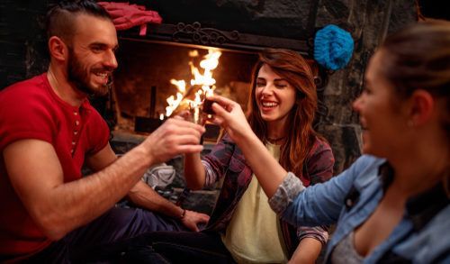 Friends toasting by the fire at a cozy cabin