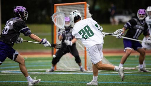 Lacrosse game being played indoors on turf.