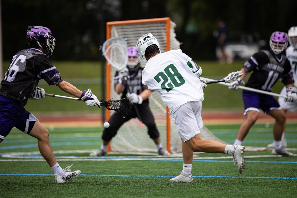 Lacrosse game being played indoors on turf.