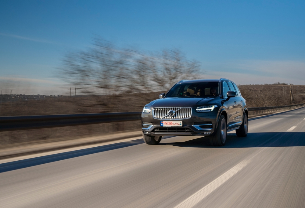 Isolated Volvo car driving down a road with a blurred landscape.