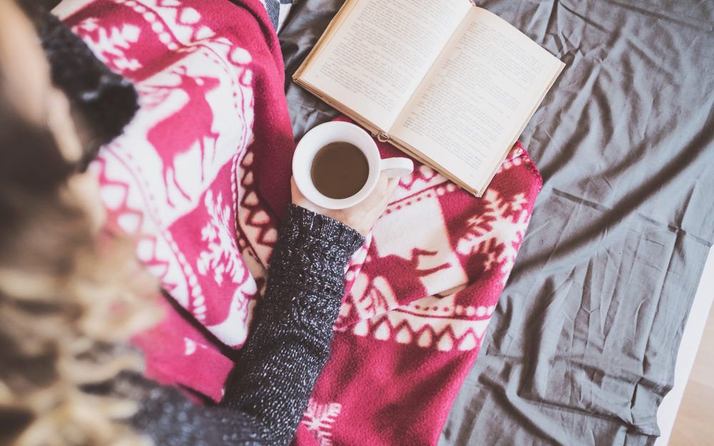Person reading with tea and a blanket