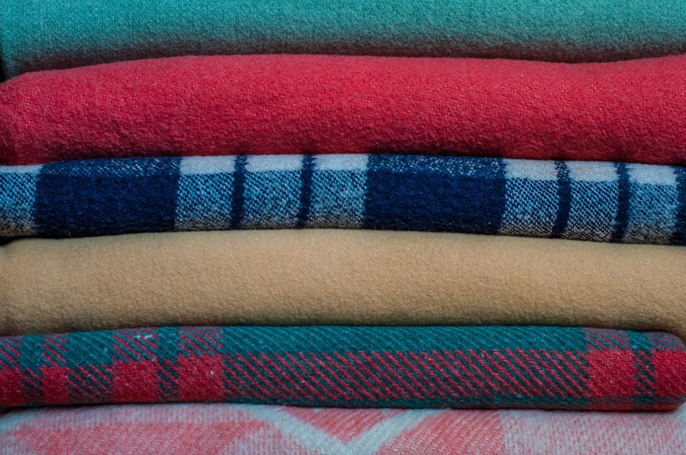 Patterned and coloured blankets stacked on top of each other.