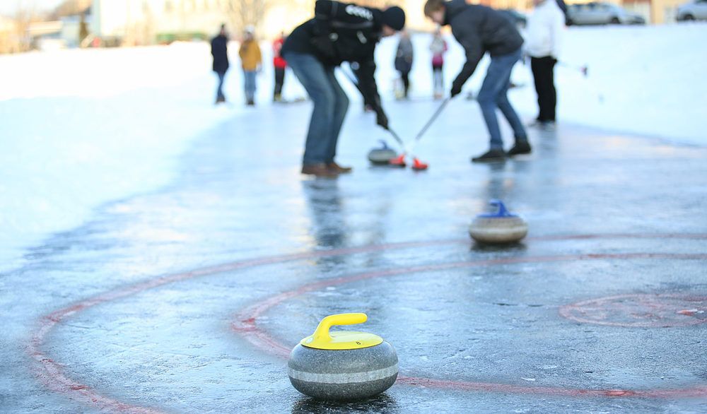People curling outdoors on a frozen lake.