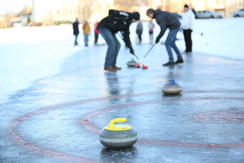 People curling outdoors on a frozen lake.