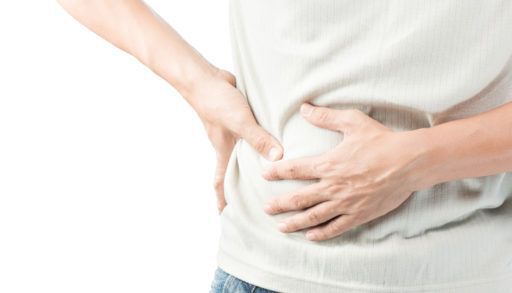 Person in a white shirt holding their stomach in pain.