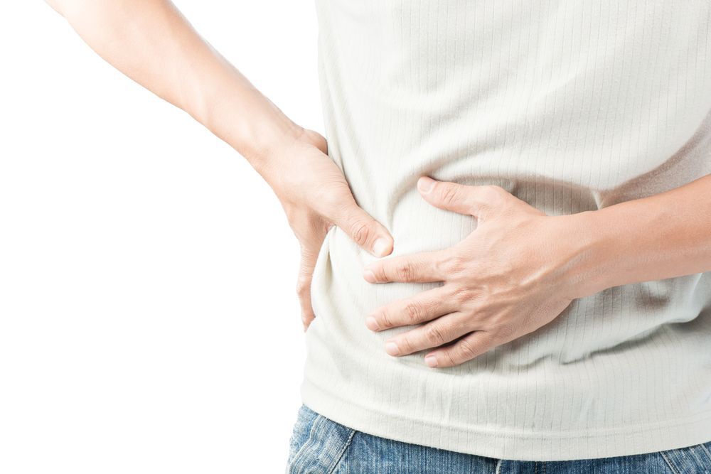 Person in a white shirt holding their stomach in pain.