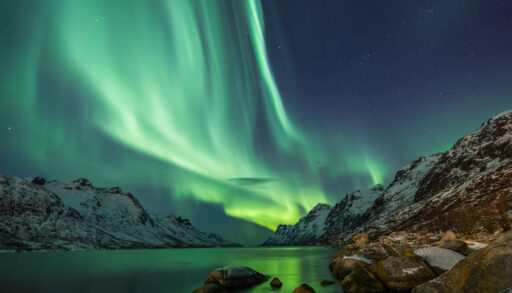 Northern lights above water and mountain landscape.