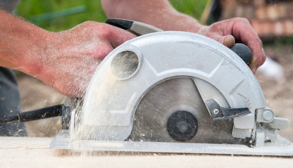 Man using a hand power saw to cut wood.