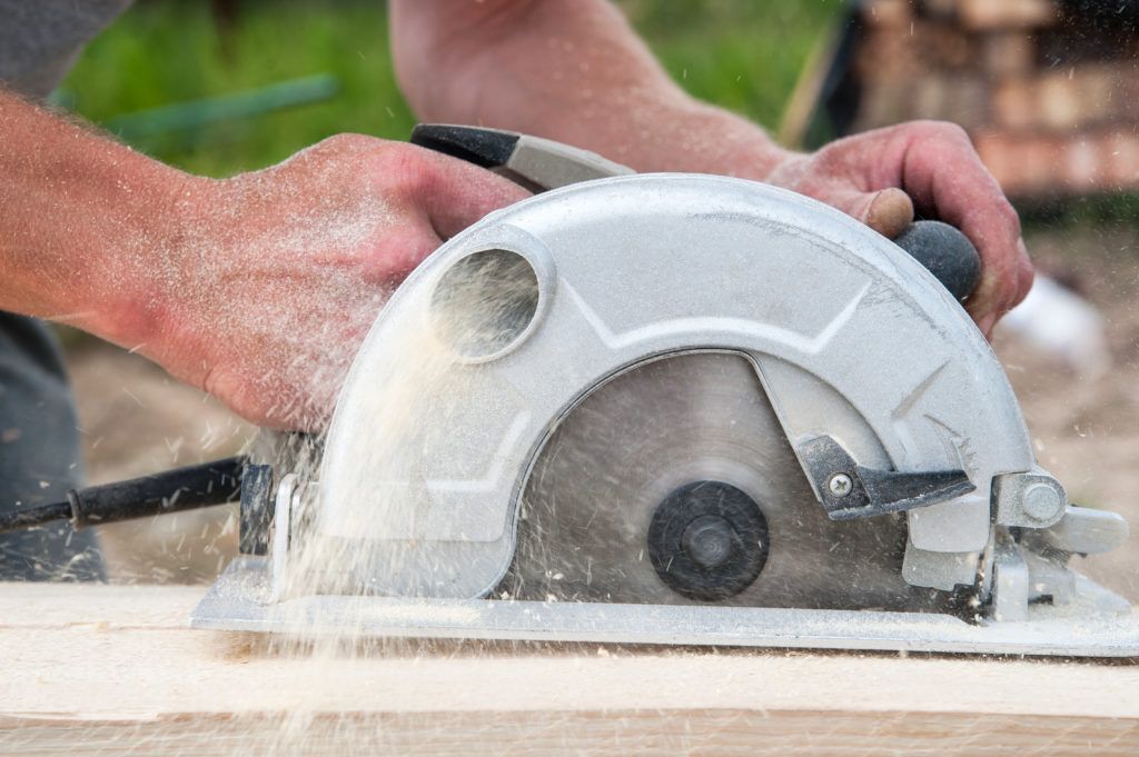 Man using a hand power saw to cut wood.
