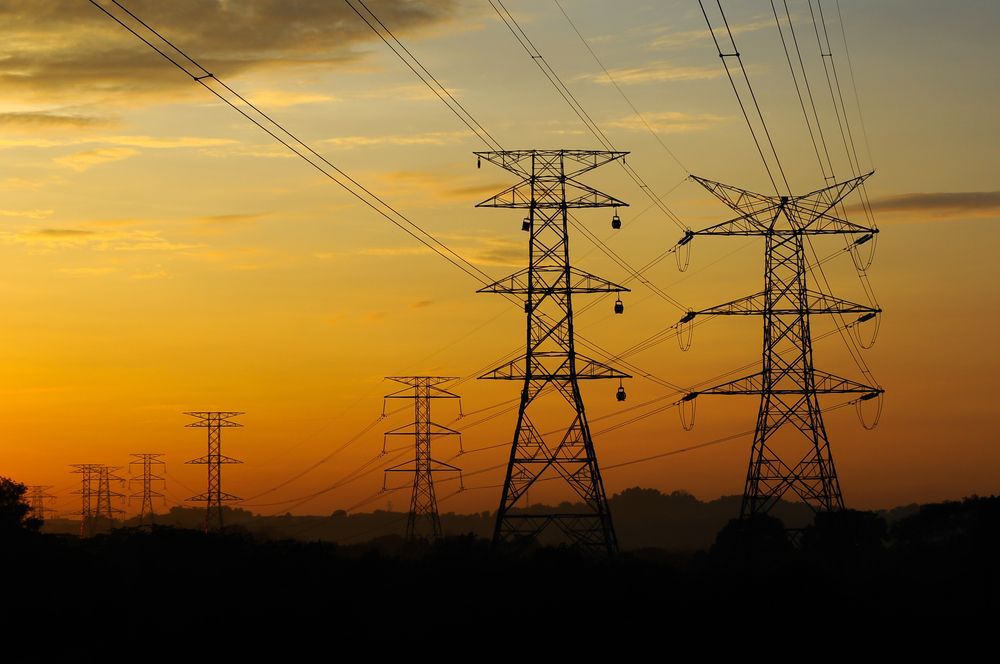 High voltage power towers and lines at sunset.