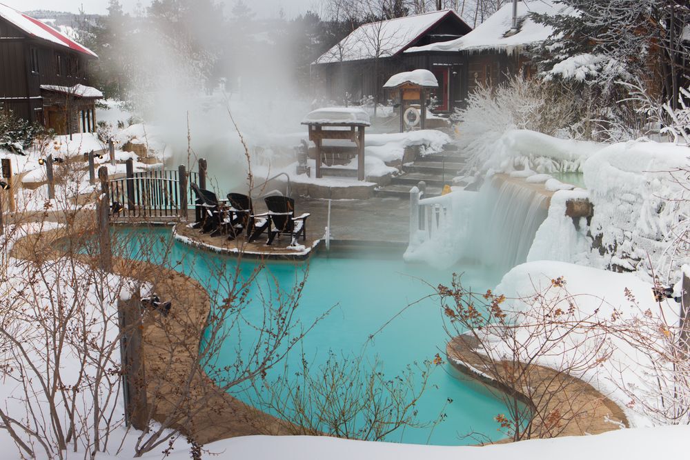 Outdoor hot springs spa covered in snow.