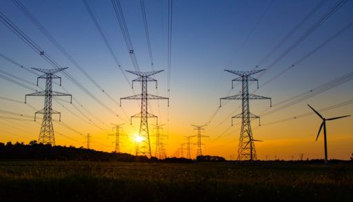 Sun setting behind hydro power towers and lines.