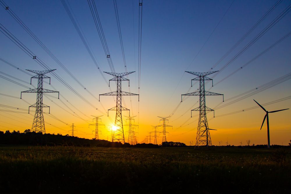 Sun setting behind hydro power towers and lines.