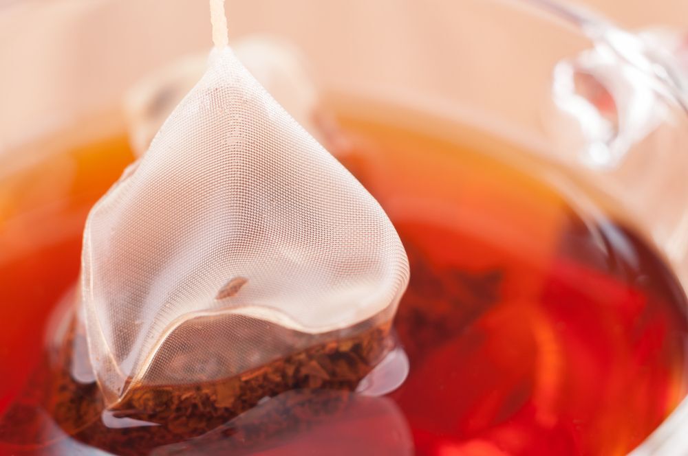 Mesh tea bag steeping in hot water.
