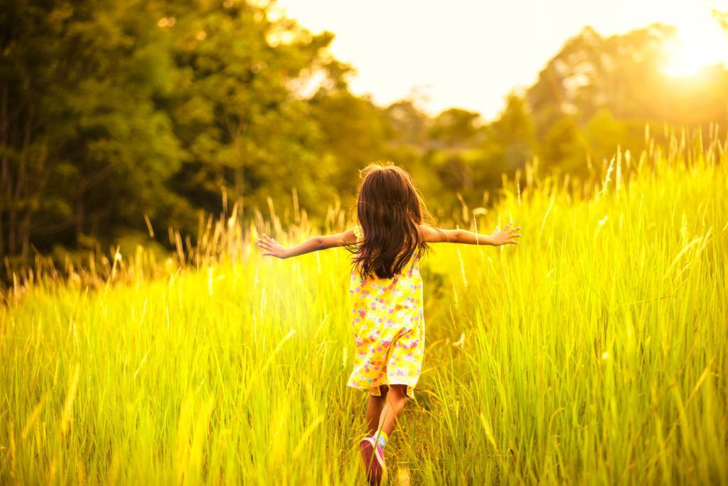 Little girl running in a meadow at sunset.