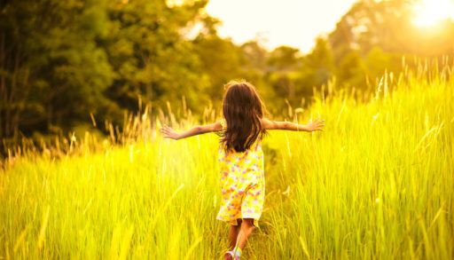 Little girl running in a meadow at sunset.