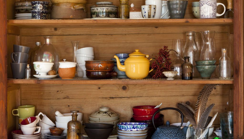 Ceramic kitchen equipment on wooden shelves.