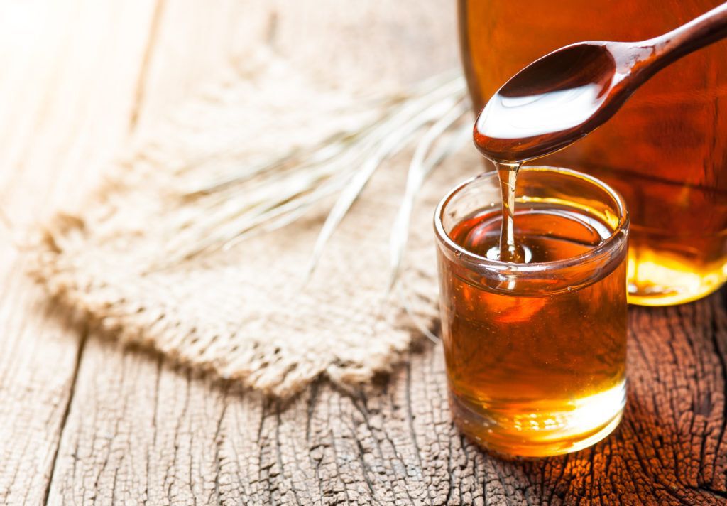 Glass jar of maple syrup on a wooden table.