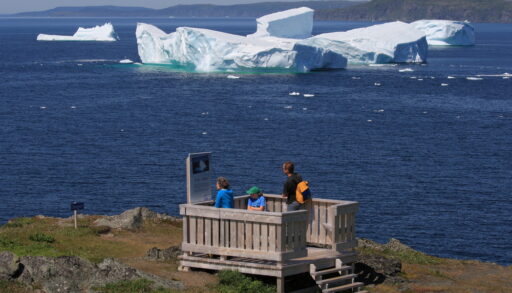 Large iceberg off the coast of Newfoundland with a view spot on land.
