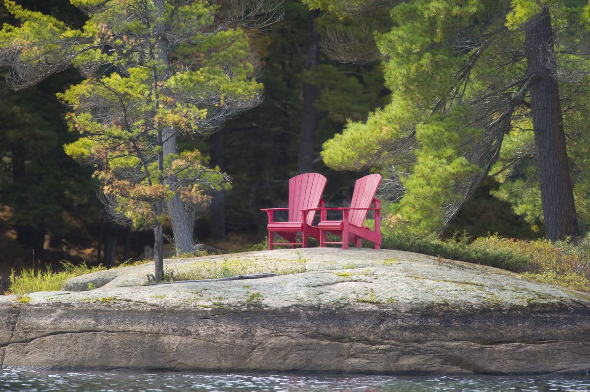 Two red Muskoka chairs on a rock