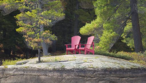 Two red Muskoka chairs on a rock