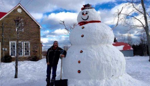 Man standing next to Frosty, the oversized snowman
