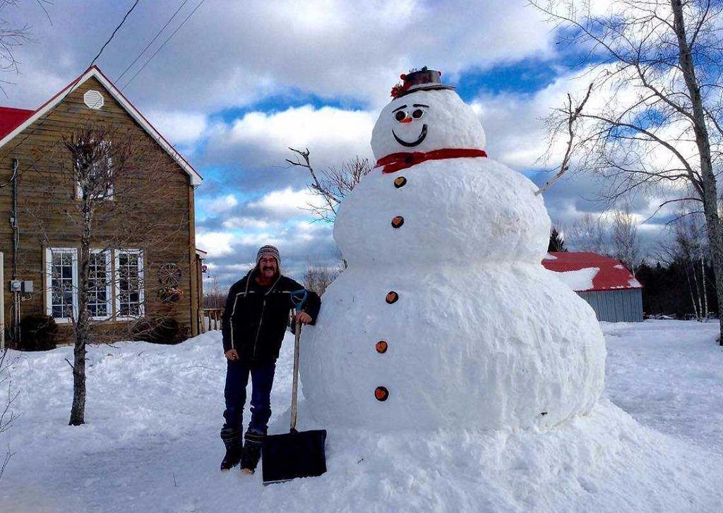 Man standing next to Frosty, the oversized snowman