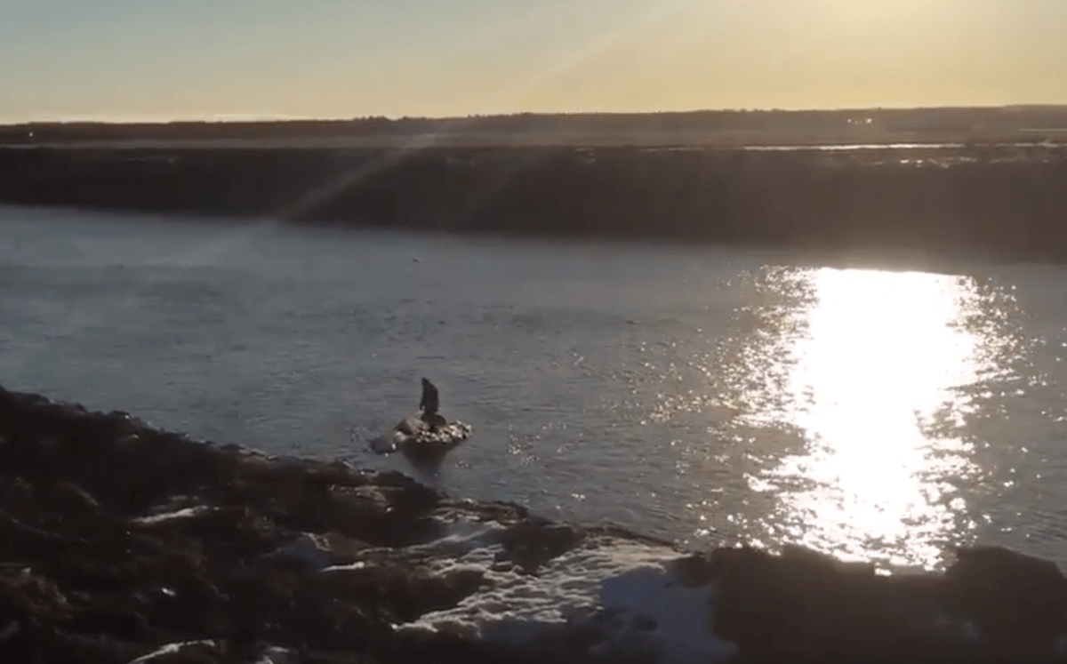 Man standing on ice floe as it floats downriver