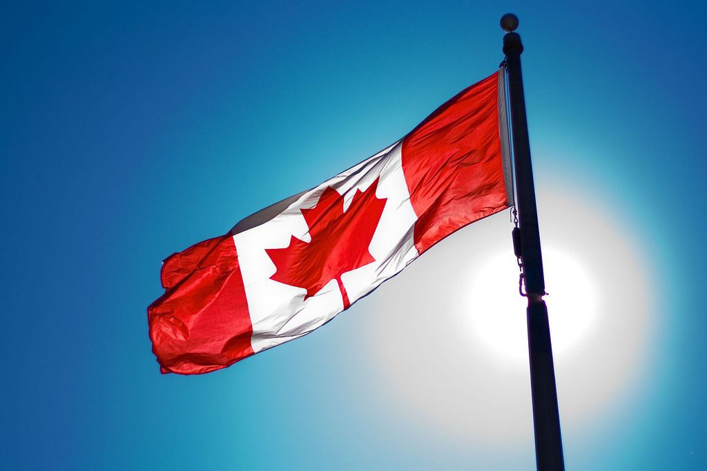 A Canadian flag in front of the sun