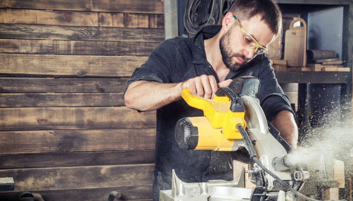 man using a saw in a workshop