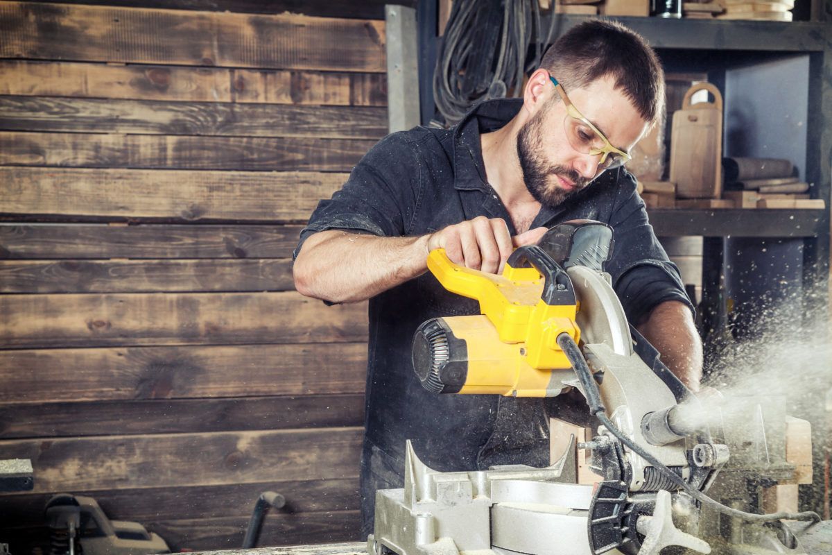 man using a saw in a workshop