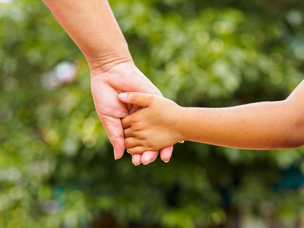 Person holding a child's hand