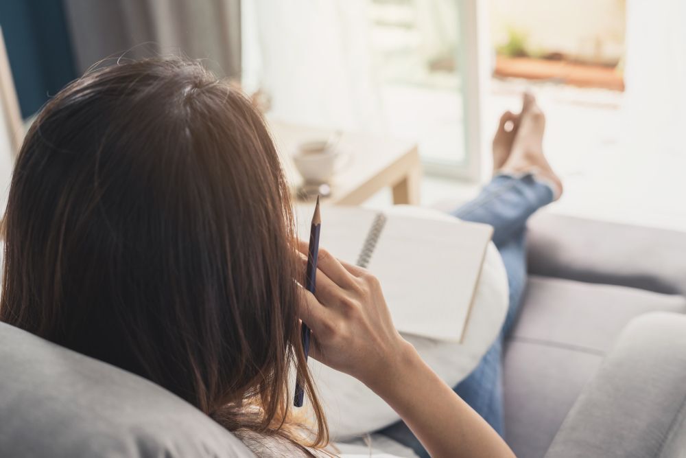 Woman writes in diary while sitting with her feet up