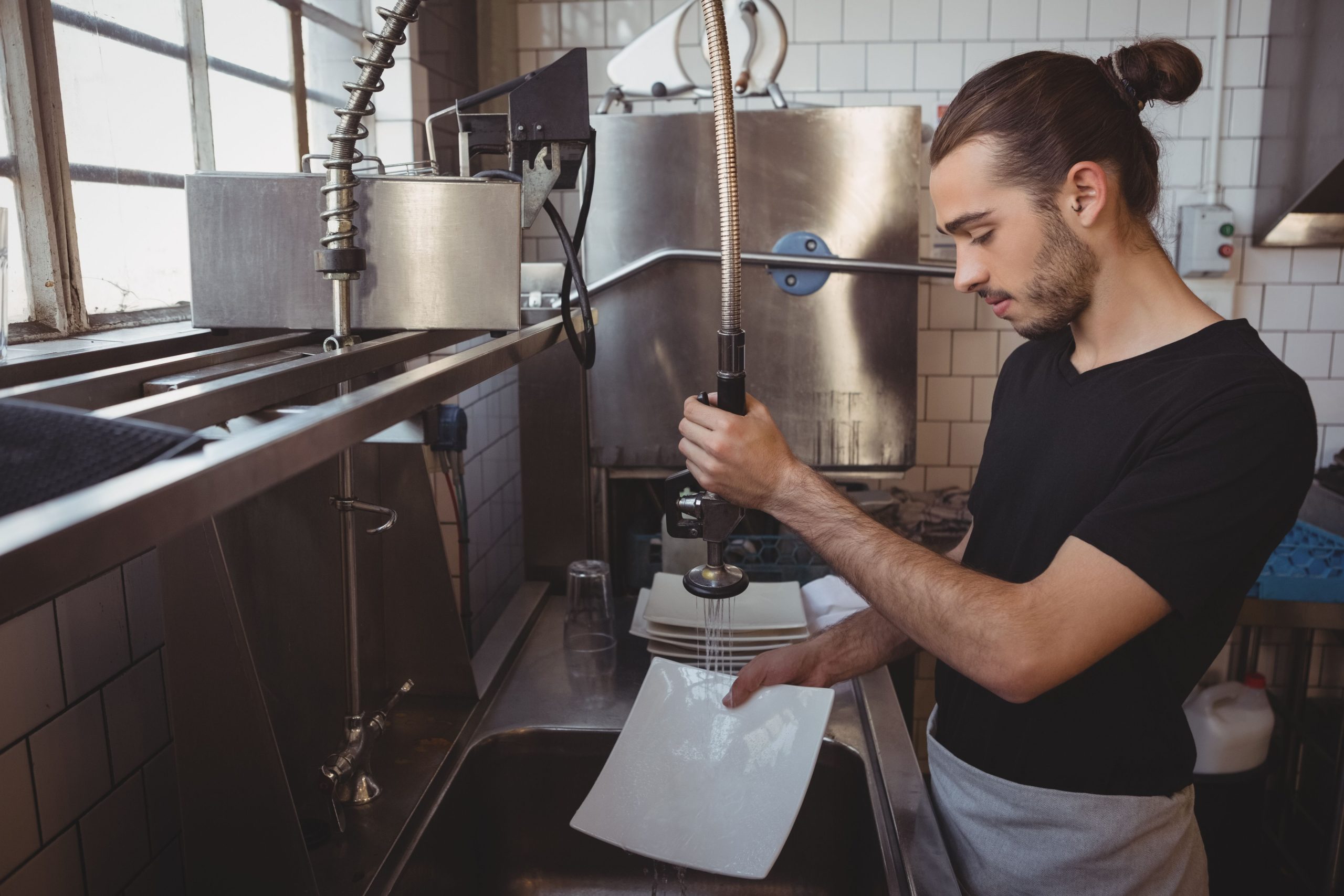 young-man-with-long-hair-washing-dishes