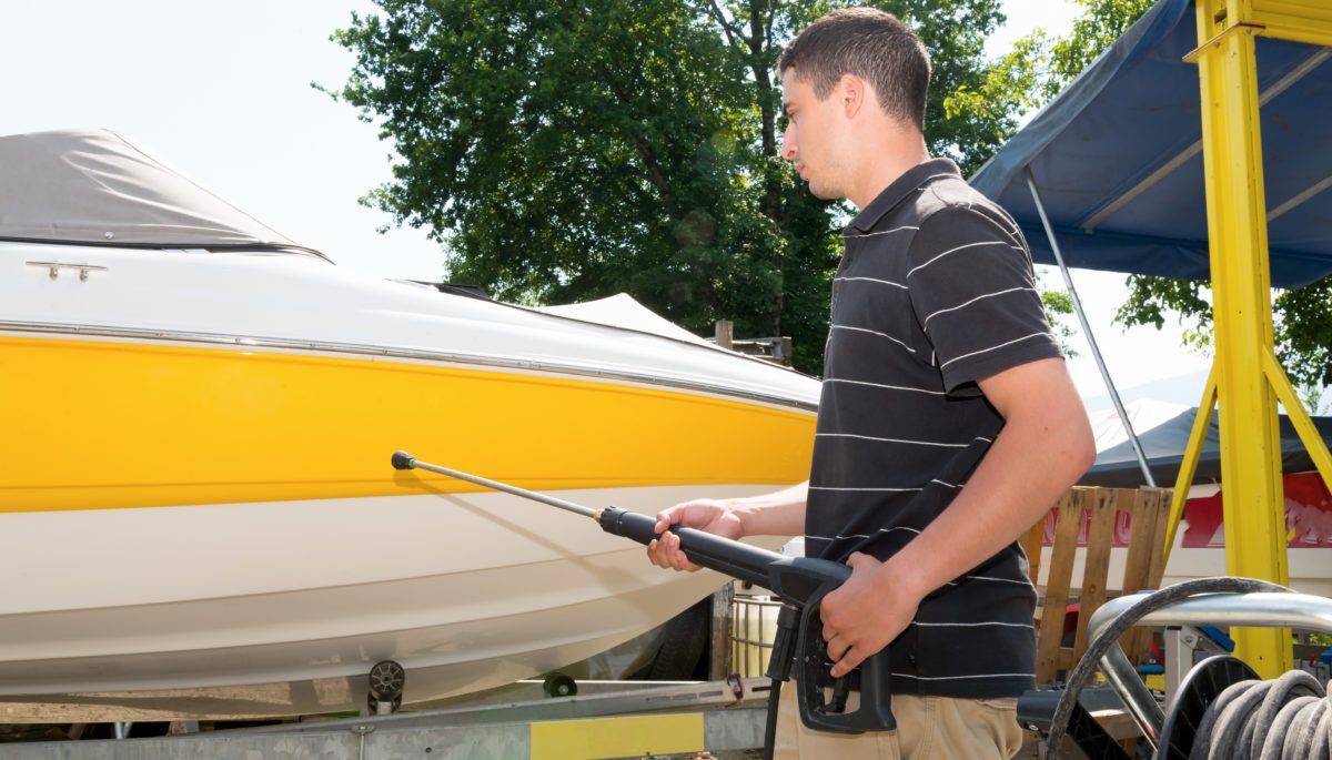 young-man-pressure-washes-the-side-of-a-boat