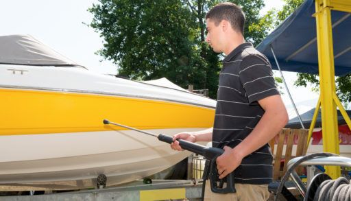 young-man-pressure-washes-the-side-of-a-boat