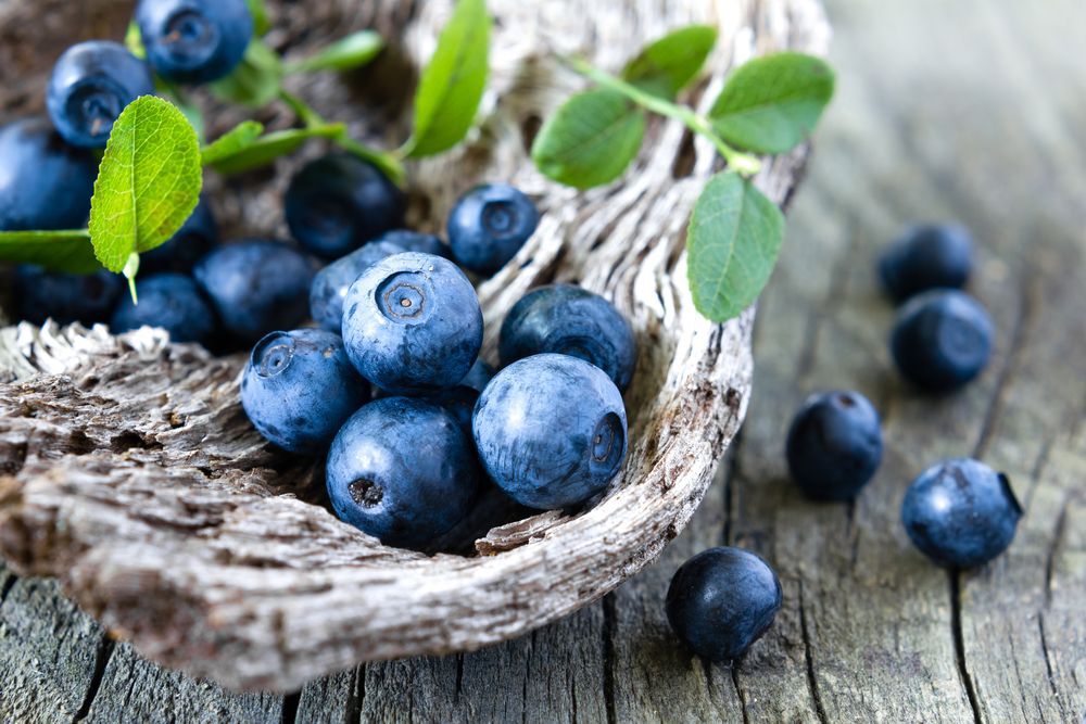 A woven basket of blueberries on a wooden table