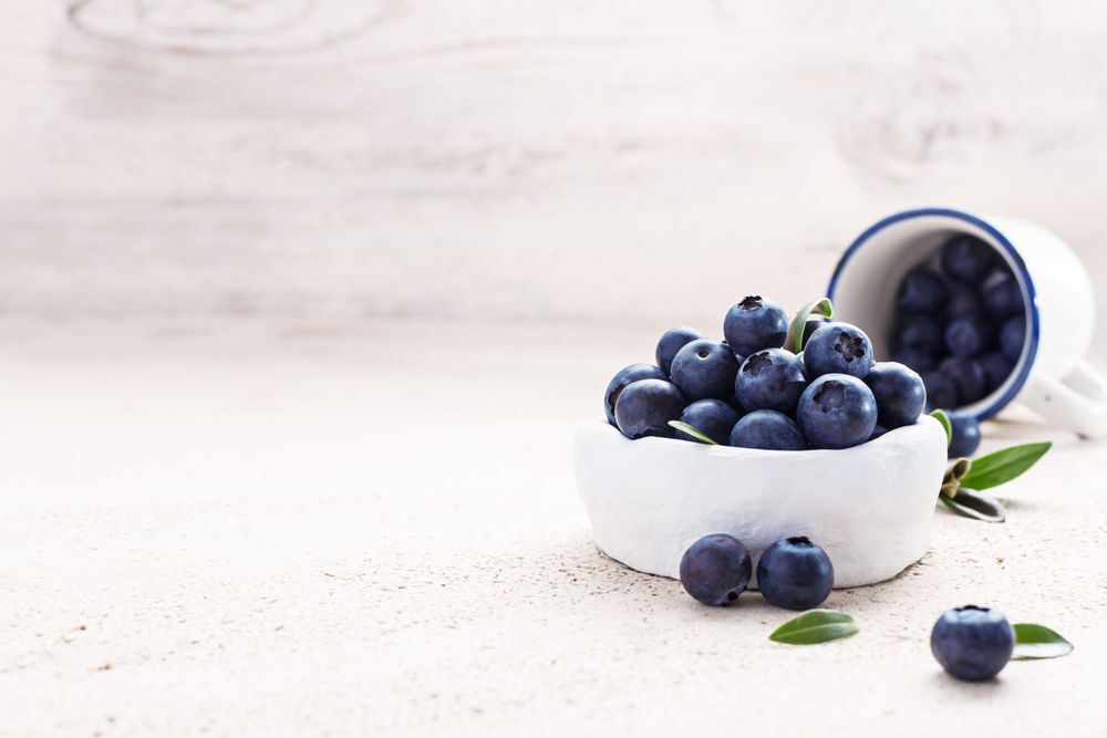 Blueberries in white ceramic bowls on a wooden table