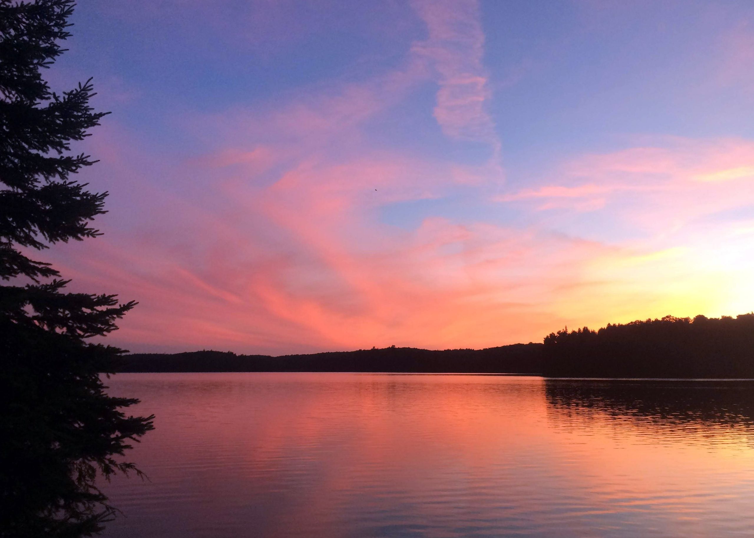 a west-facing view of a camp site on a lake at sunset.