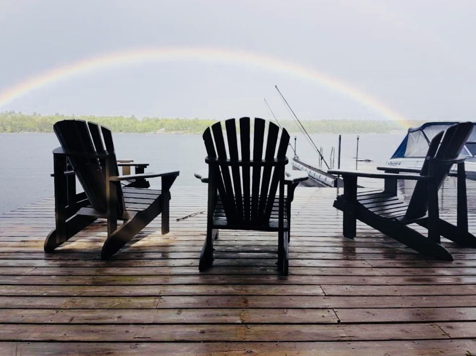 A rainbow and Muskoka chairs on a dock on Go Home Lake