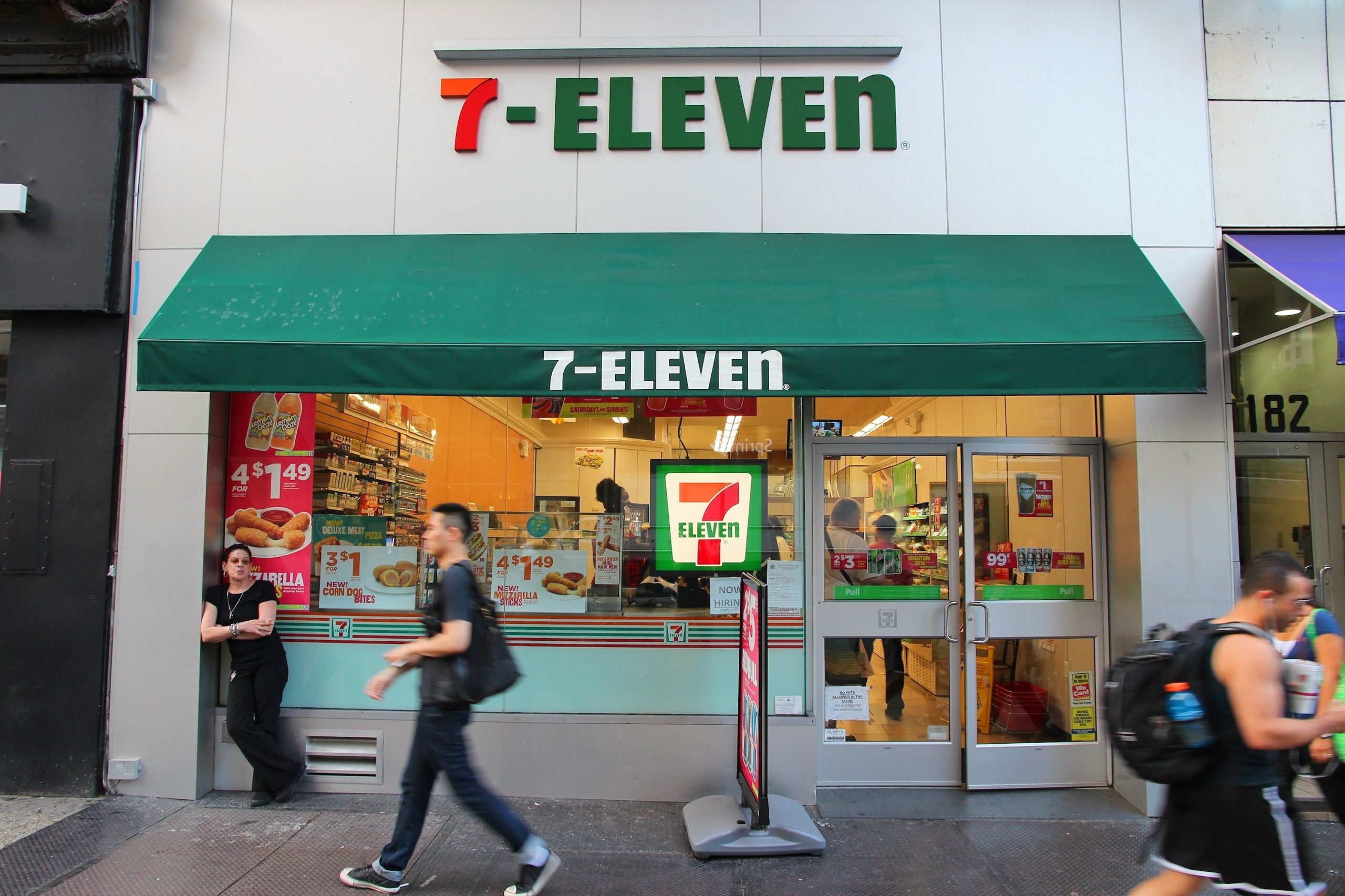 People walk past 7-Eleven convenience store in New York, USA