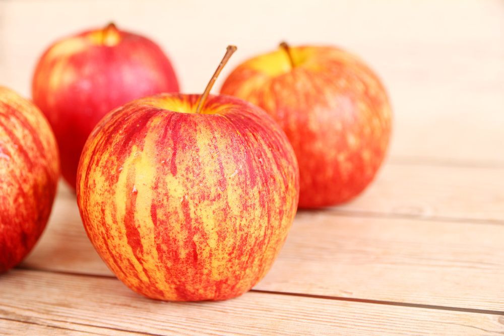 Honeycrisp apples sit on a wooden table