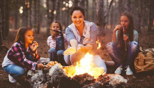 Family sitting around a fall campfire enjoying the warmth of the fire and a campfire snack