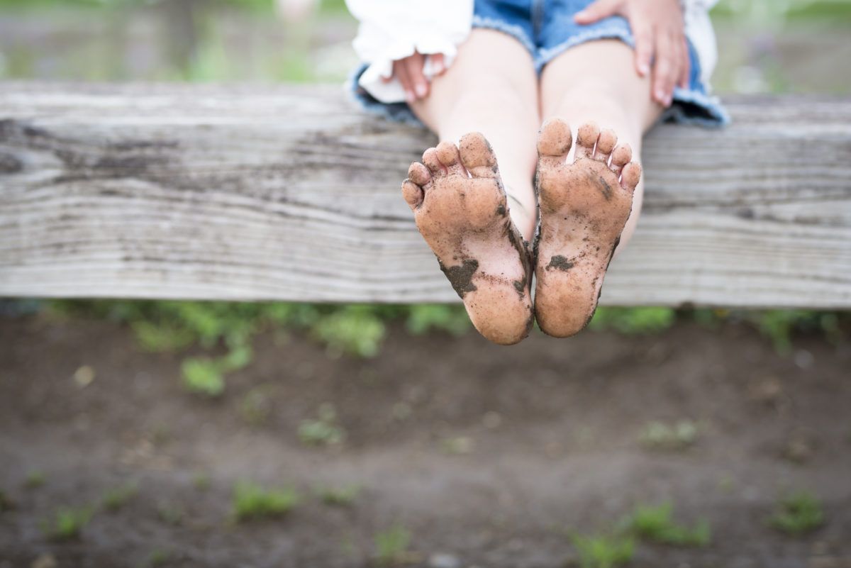A-child-with-dirty-feet-sits-on-a-fence