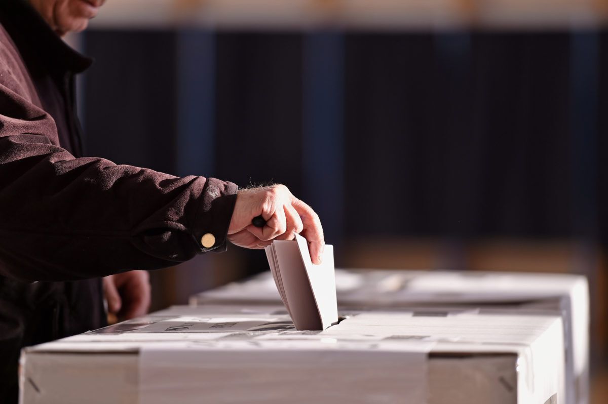 Hand of a person casting a vote into the ballot box during an election