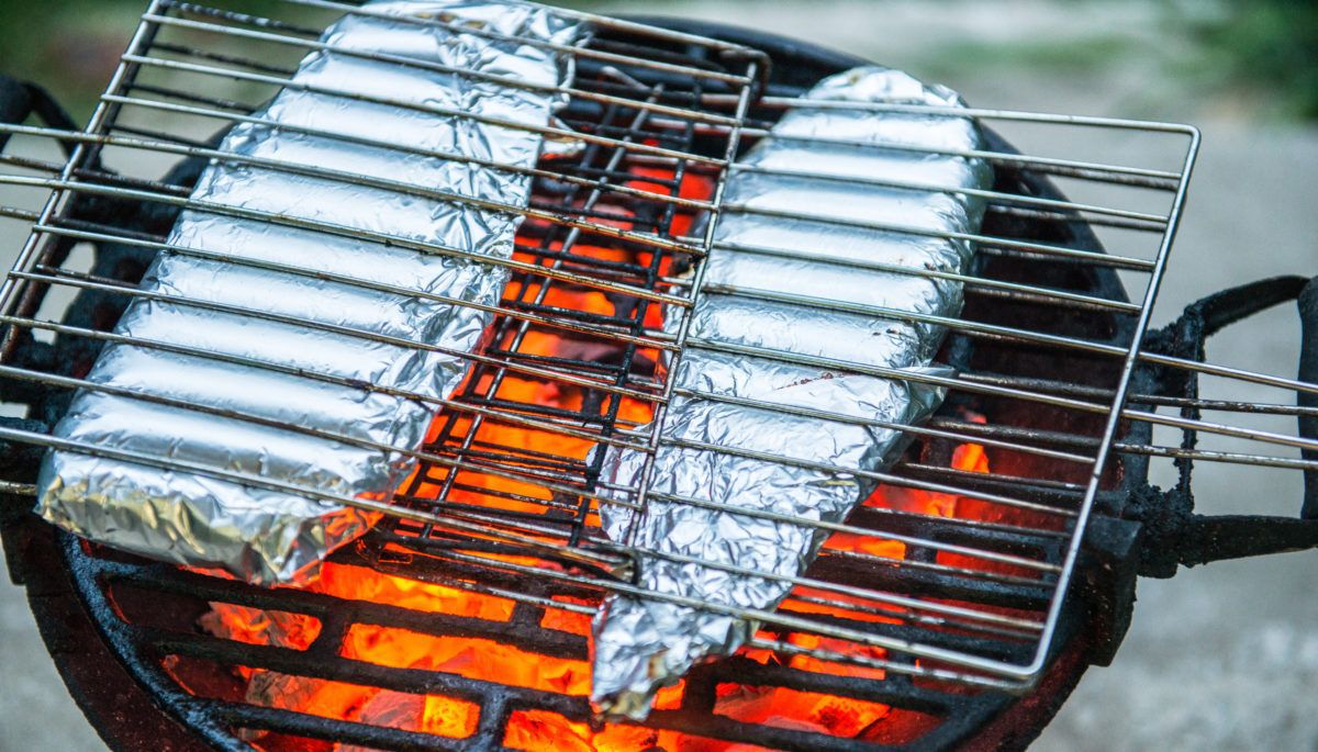Fish fillets in aluminum foil cooking on the grill